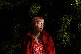 Portrait of the poet Helen Mort, standing in front of trees