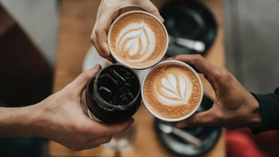 Three hands holding coffee cups