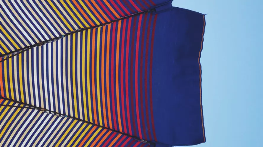 Striped beach parasol against blue sky