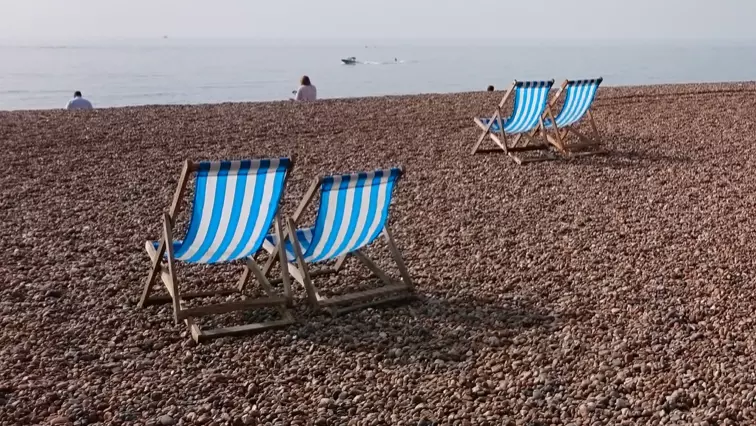 Brighton beach with four blue and white striped deckchairs