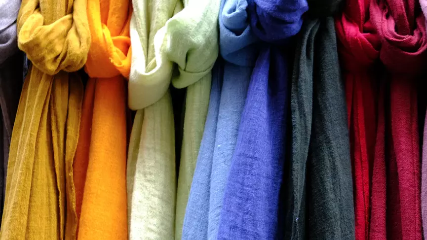 A range of different coloured knotted scarves hanging in a row