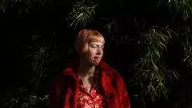 Portrait of the poet Helen Mort, standing in front of trees